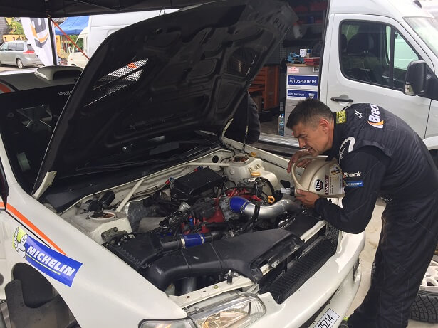 Krzysztof Hołowczyc wlewa olej do swojego Subaru Impreza